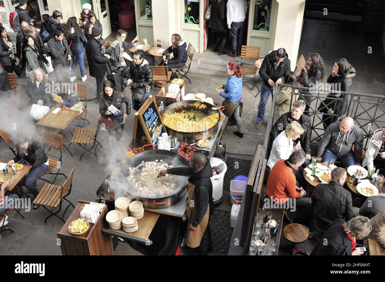 People at restaurant, chef preparing paella in large frying pans. Covent Garden Market in London UK. Stock Photo