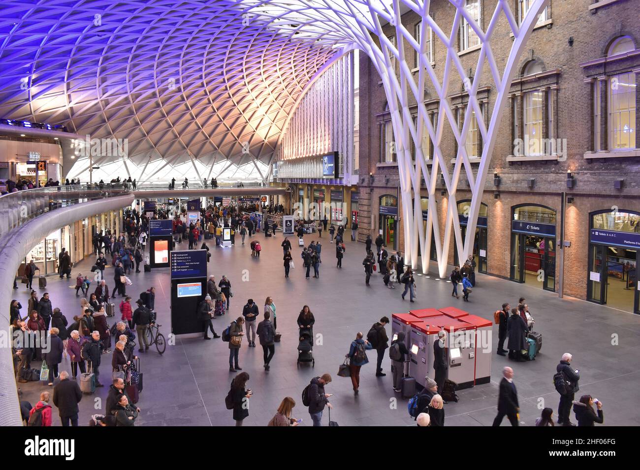 King's Cross railway station modern terminal building with steel roof structure, main hallway with travellers, London UK. Stock Photo