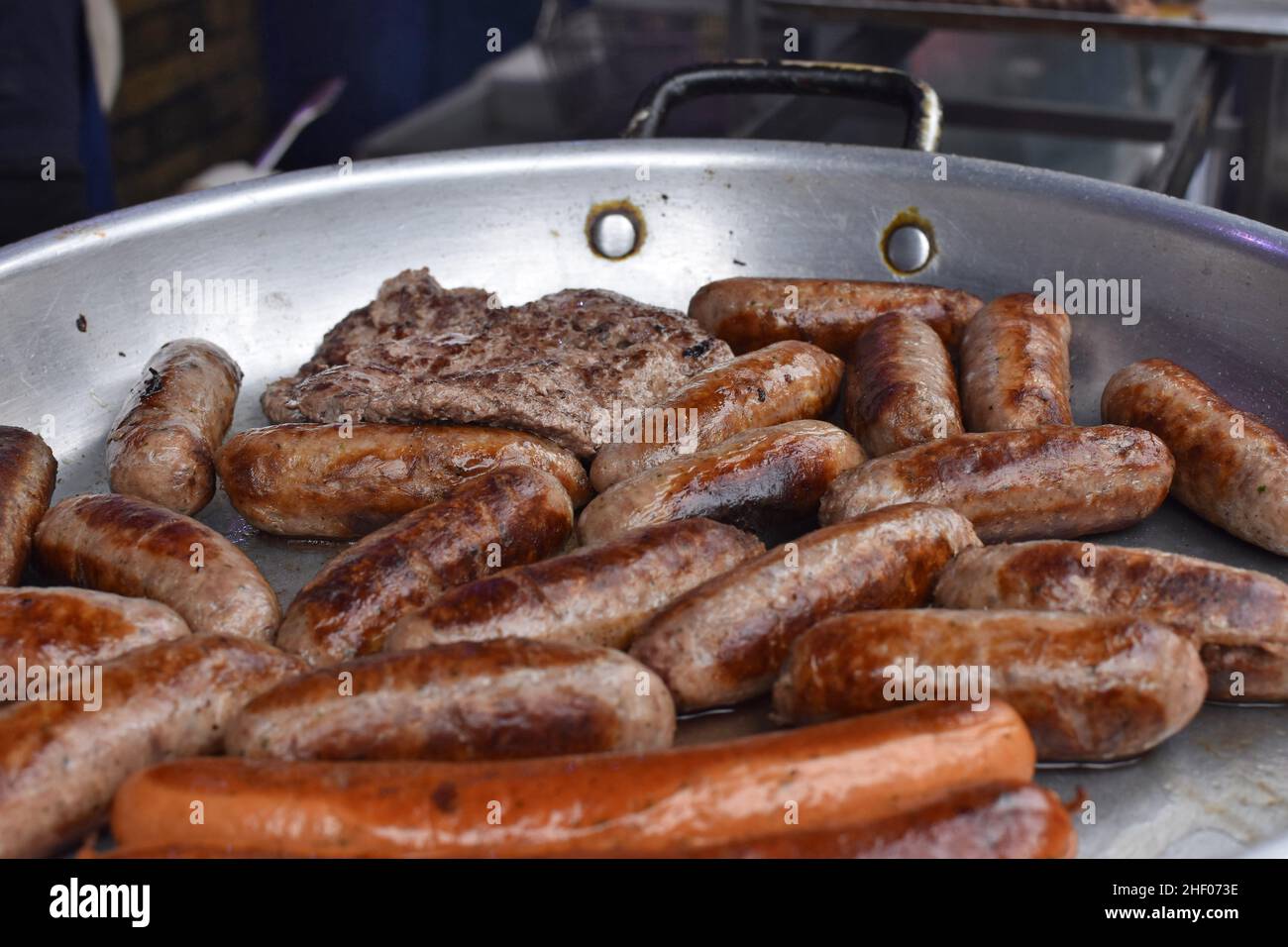 Meat and sausages in frying pan, Borough Market in Southwark London UK Stock Photo