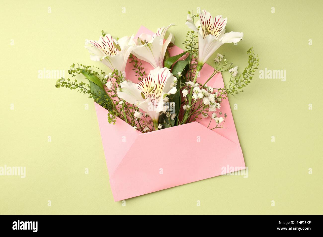 Pink envelope with flowers on green background Stock Photo