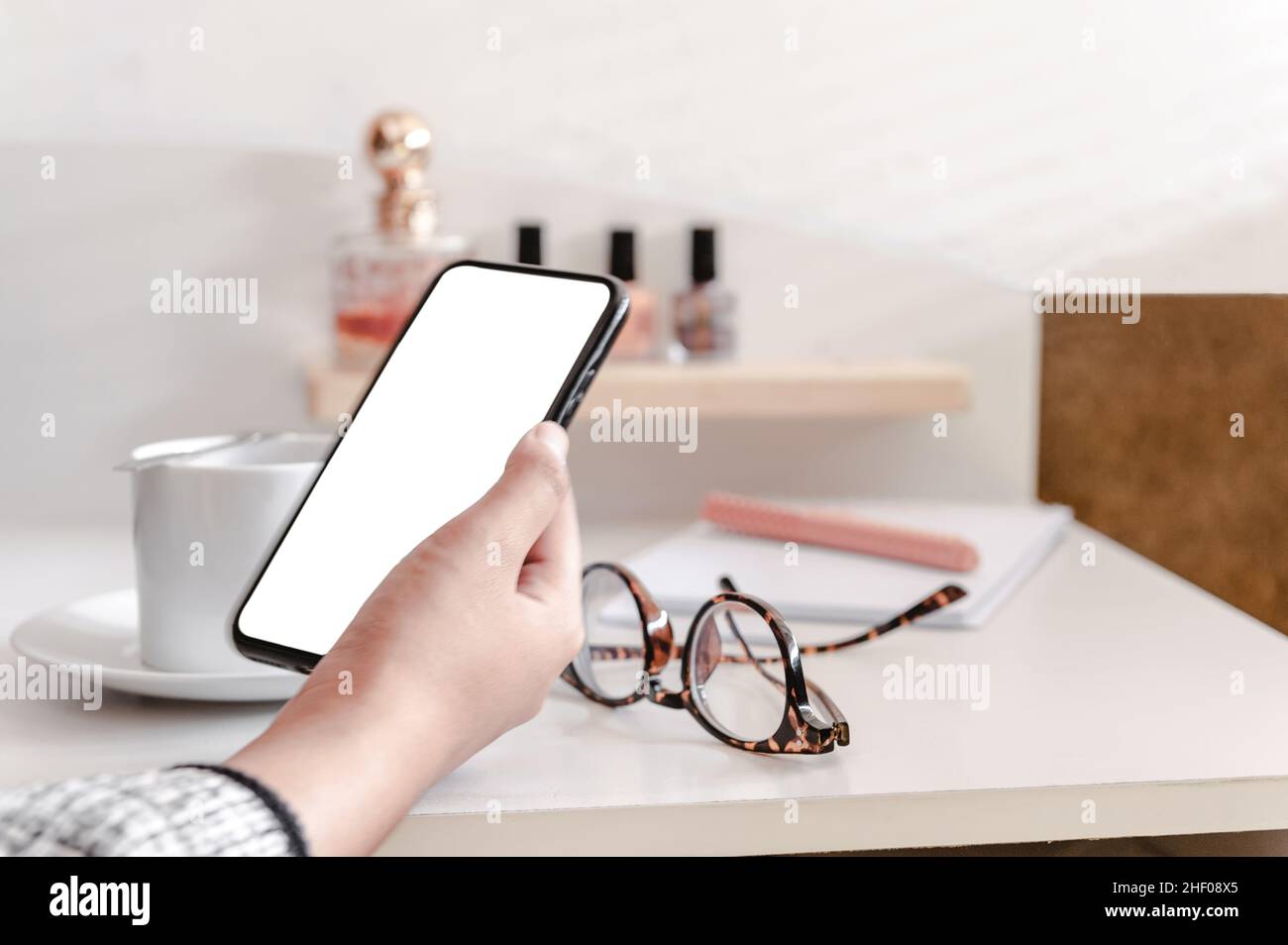 Female hand holding cellphone with white screen. Stock Photo
