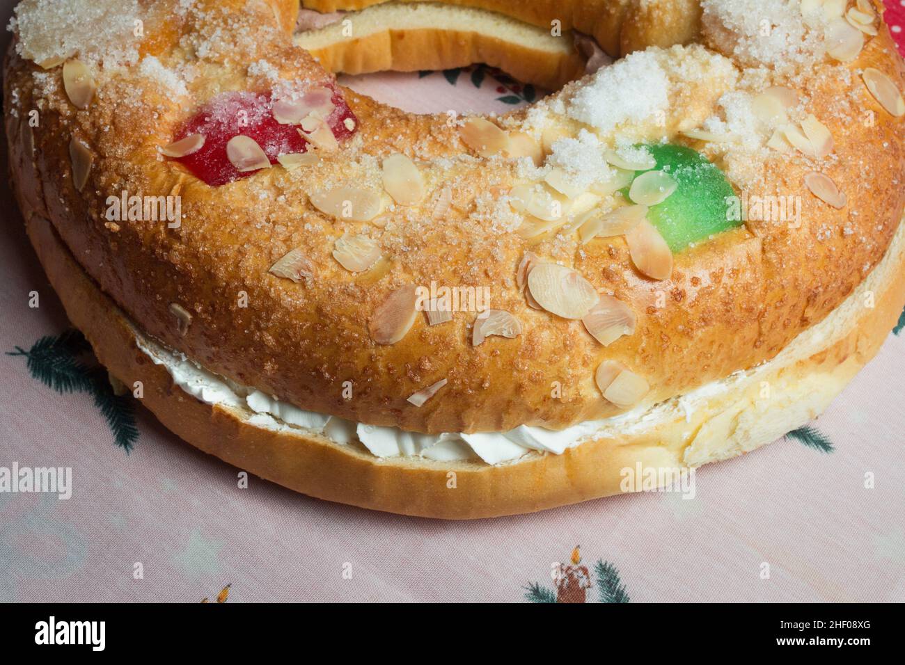 Large donut cake filling with sweet whipped cream with candied fruit adorning the top on a decorated tablecloth with Christmas motifs. Tradicional swe Stock Photo