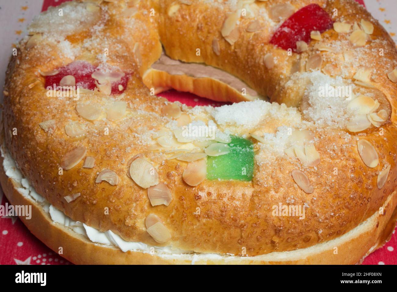 Large donut cake filling with sweet whipped cream with candied fruit adorning the top on a decorated tablecloth with Christmas motifs. Tradicional swe Stock Photo