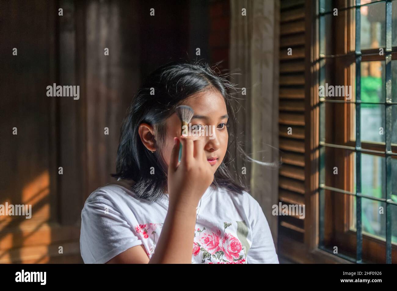 Young girl doing makeup in front of mirror. Stock Photo