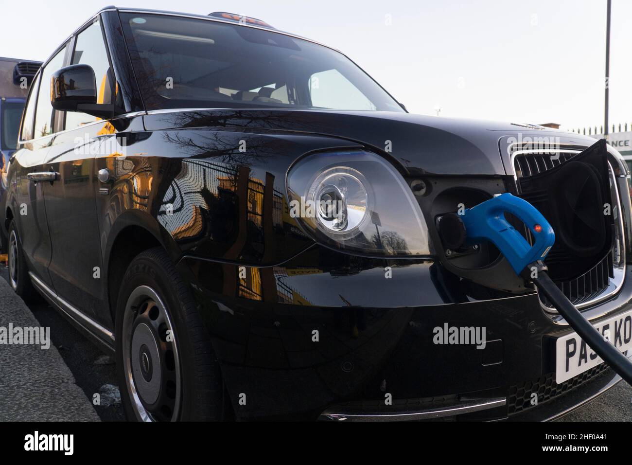 London, UK, 12 January 2022: An electric taxi recharges at a public charging point. Despite looking like a traditional black cab this vehicle has low emissions and makes less noise. Anna Watson/Alamy Stock Photo