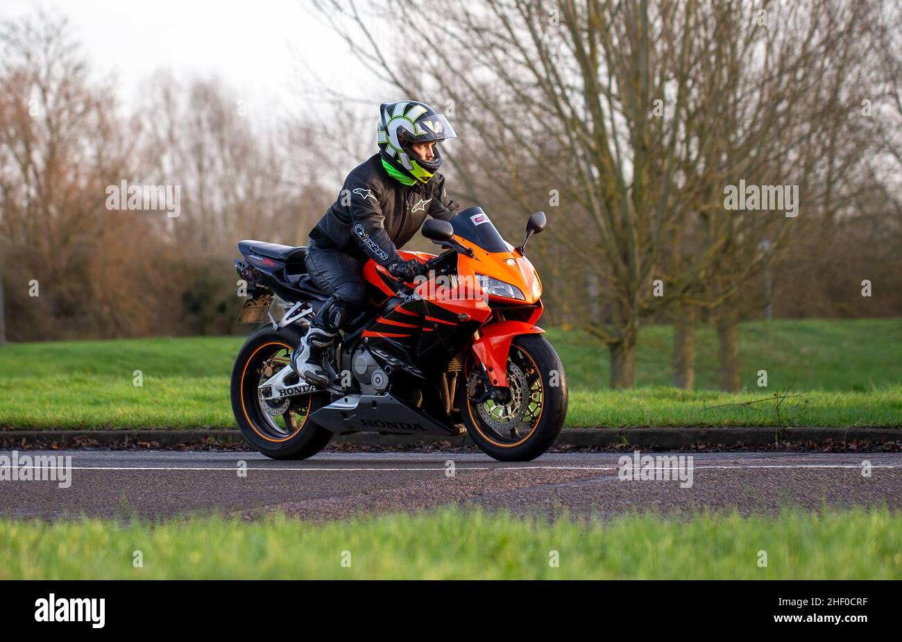 Man riding an orange Honda motorcycle Stock Photo