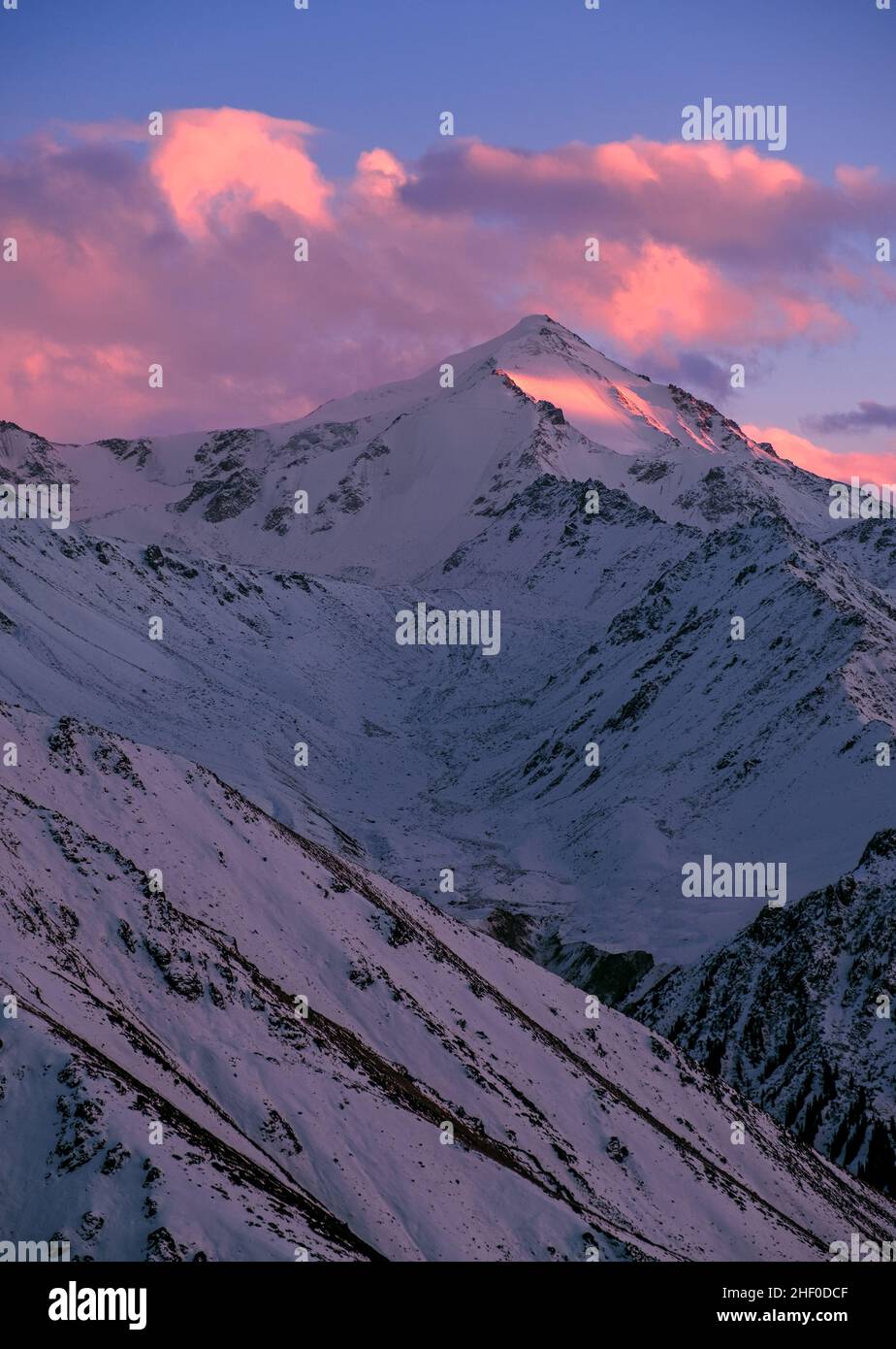 Snow-capped mountains at sunset; mountain peak against a blue sky with sunset clouds Stock Photo