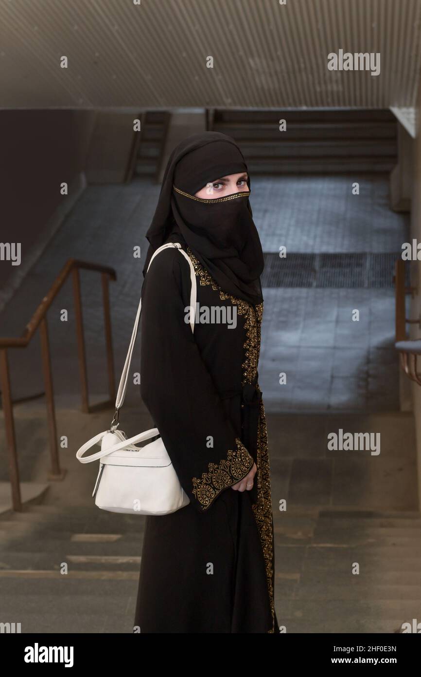 A Muslim woman in national dress walks through an underground passage. Stock Photo
