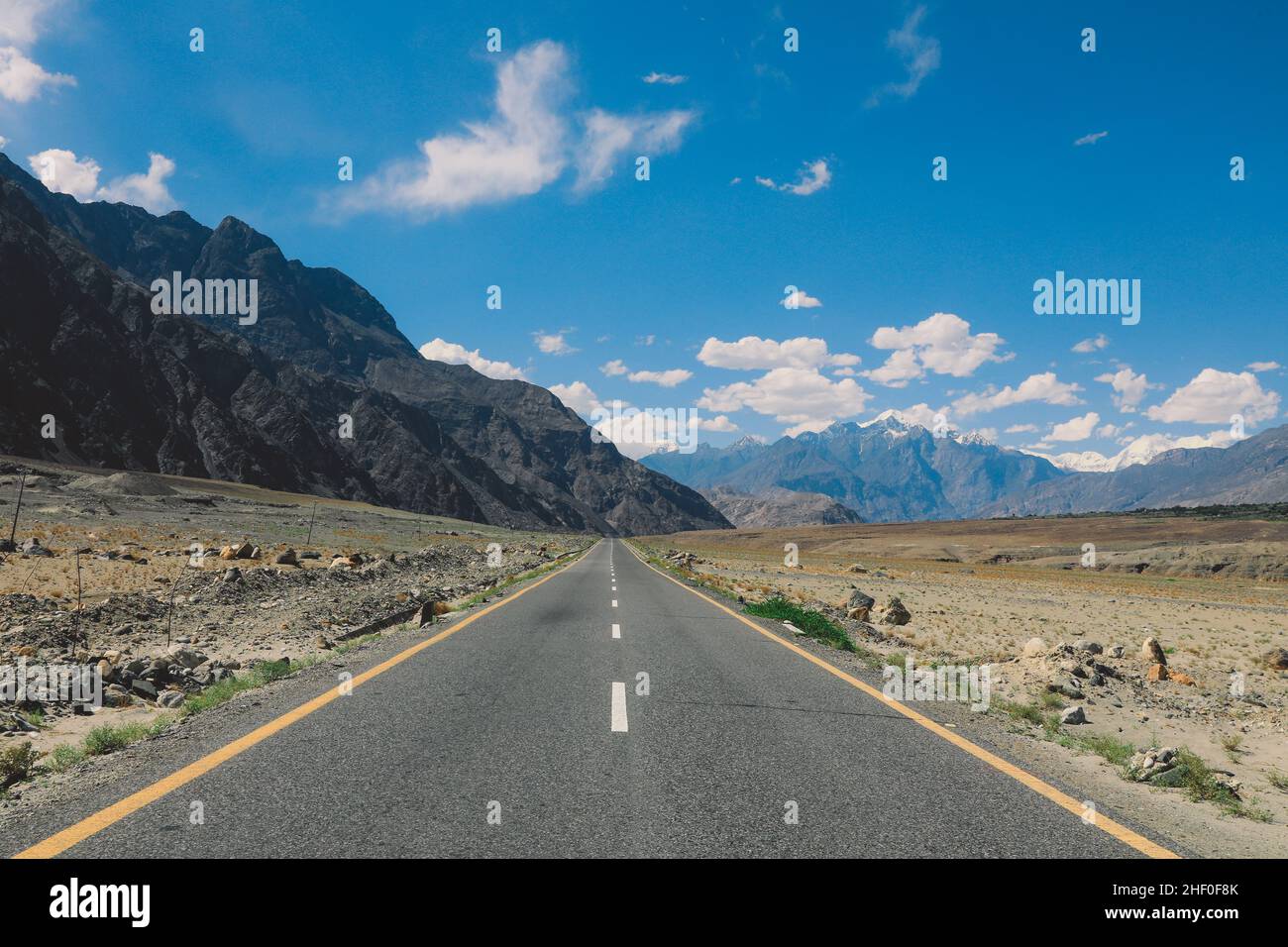 Asphalt Road in the High Gilgit Baltistan Mountains under the Blue Clouds, Pakistan Stock Photo
