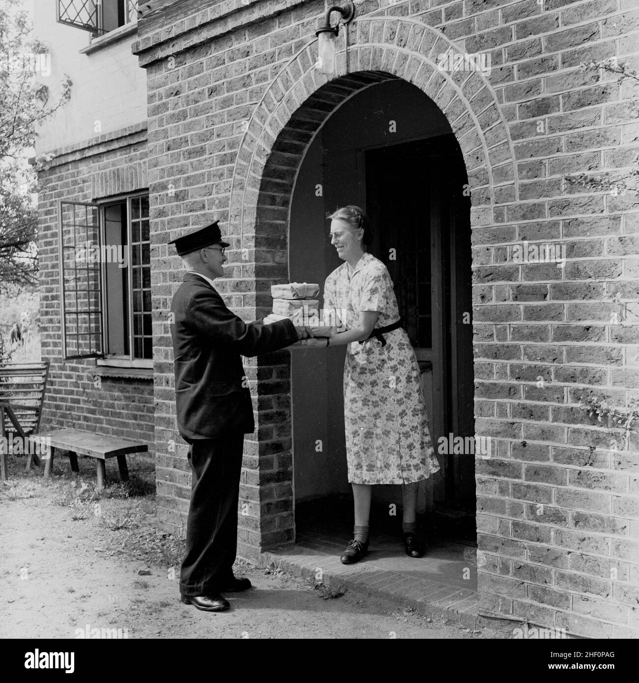 1950s, historical postman delivering parcels to a lady, England, UK. Stock Photo