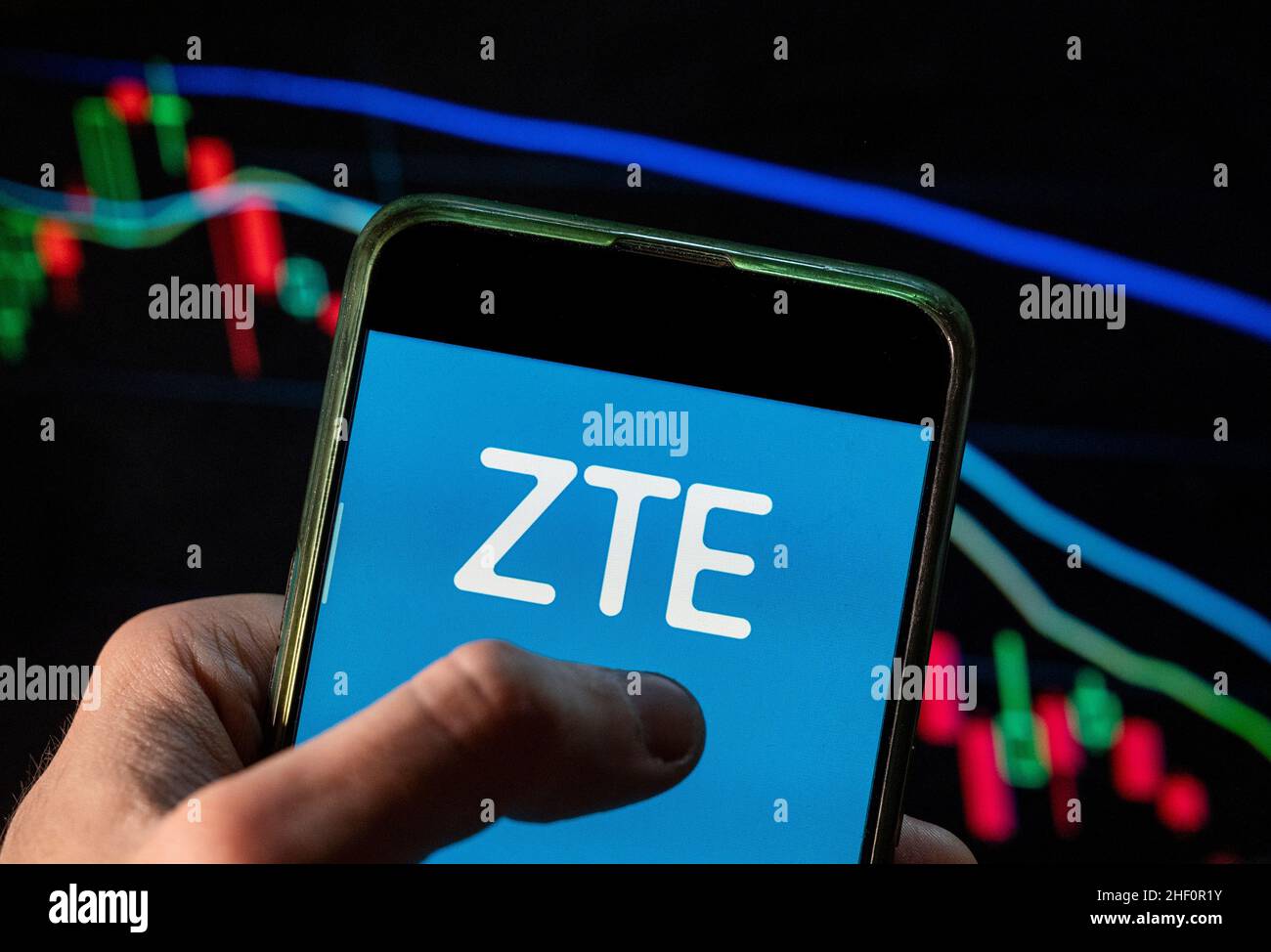 In this photo illustration the Chinese multinational telecommunications equipment and systems company ZTE logo seen displayed on a smartphone with an economic stock exchange index graph in the background. Stock Photo