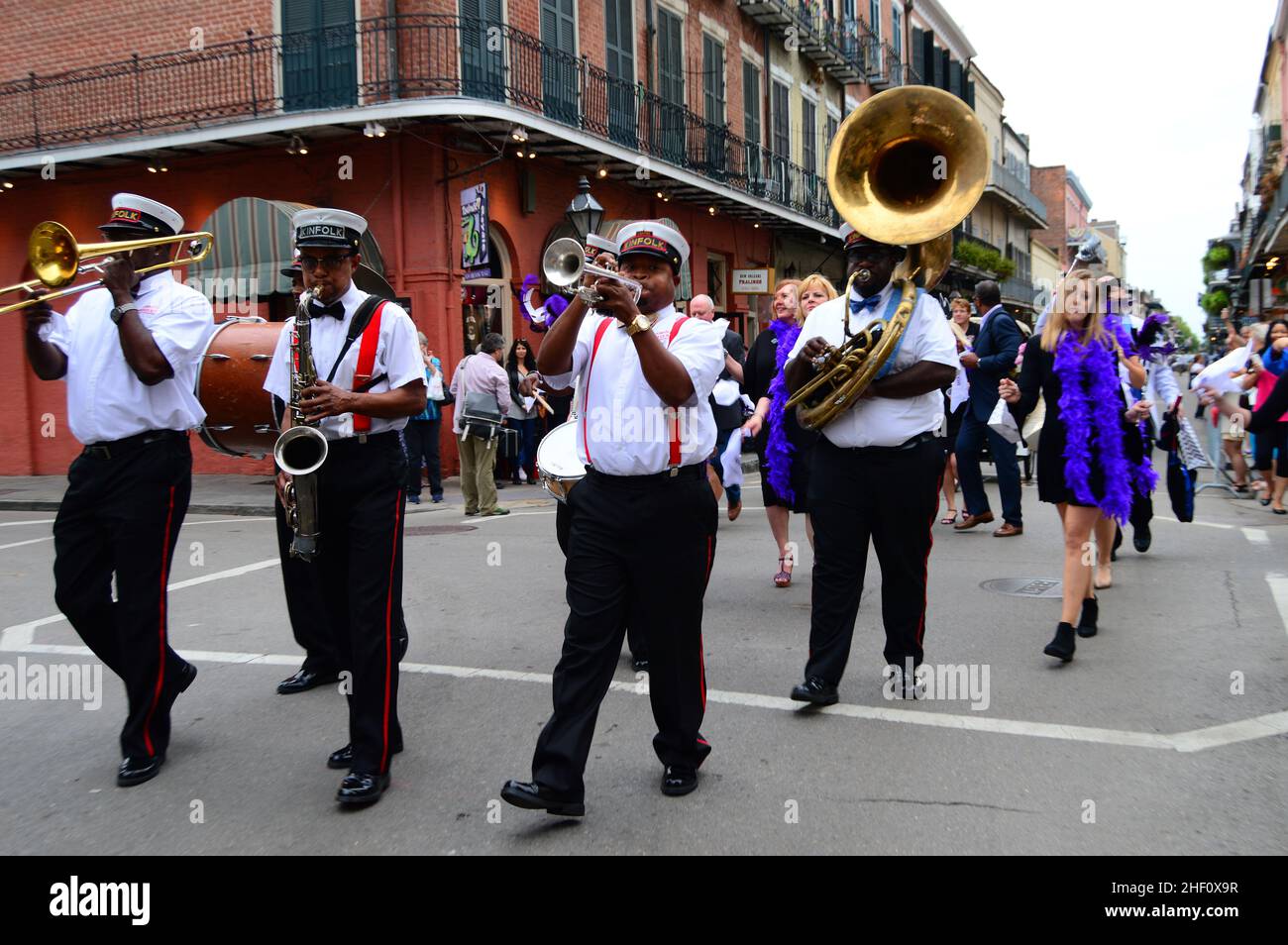 A second line brass jazz band parades down Bourbon Street in the French Quarter of New Orleans while party goers march and dance behind them Stock Photo