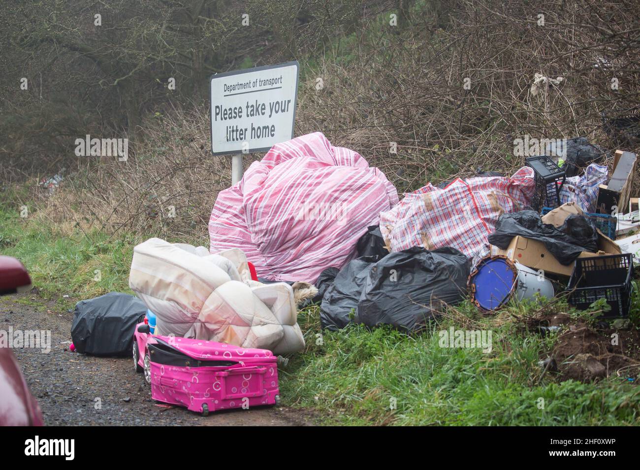 Pile of rubbish illegally dumped in a highway lay-by at the side of a ...