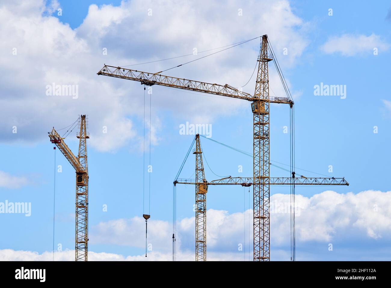 Construction cranes on background of cloudy sky Stock Photo - Alamy