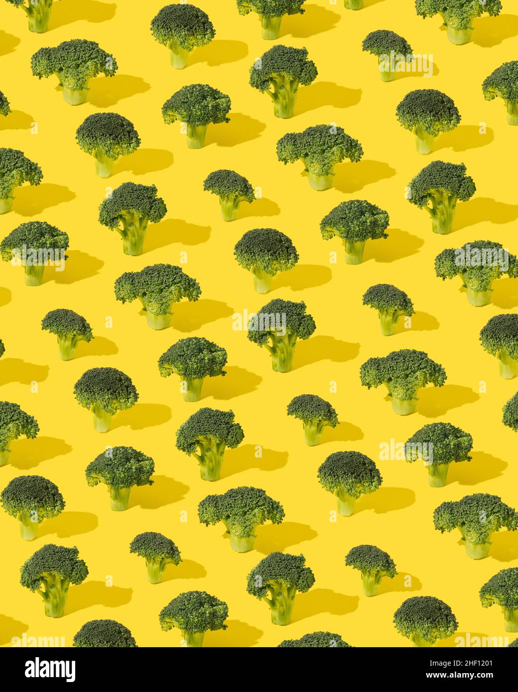 Pattern made of green broccoli flowers on a yellow background. Sustainable development minimal concept. Stock Photo