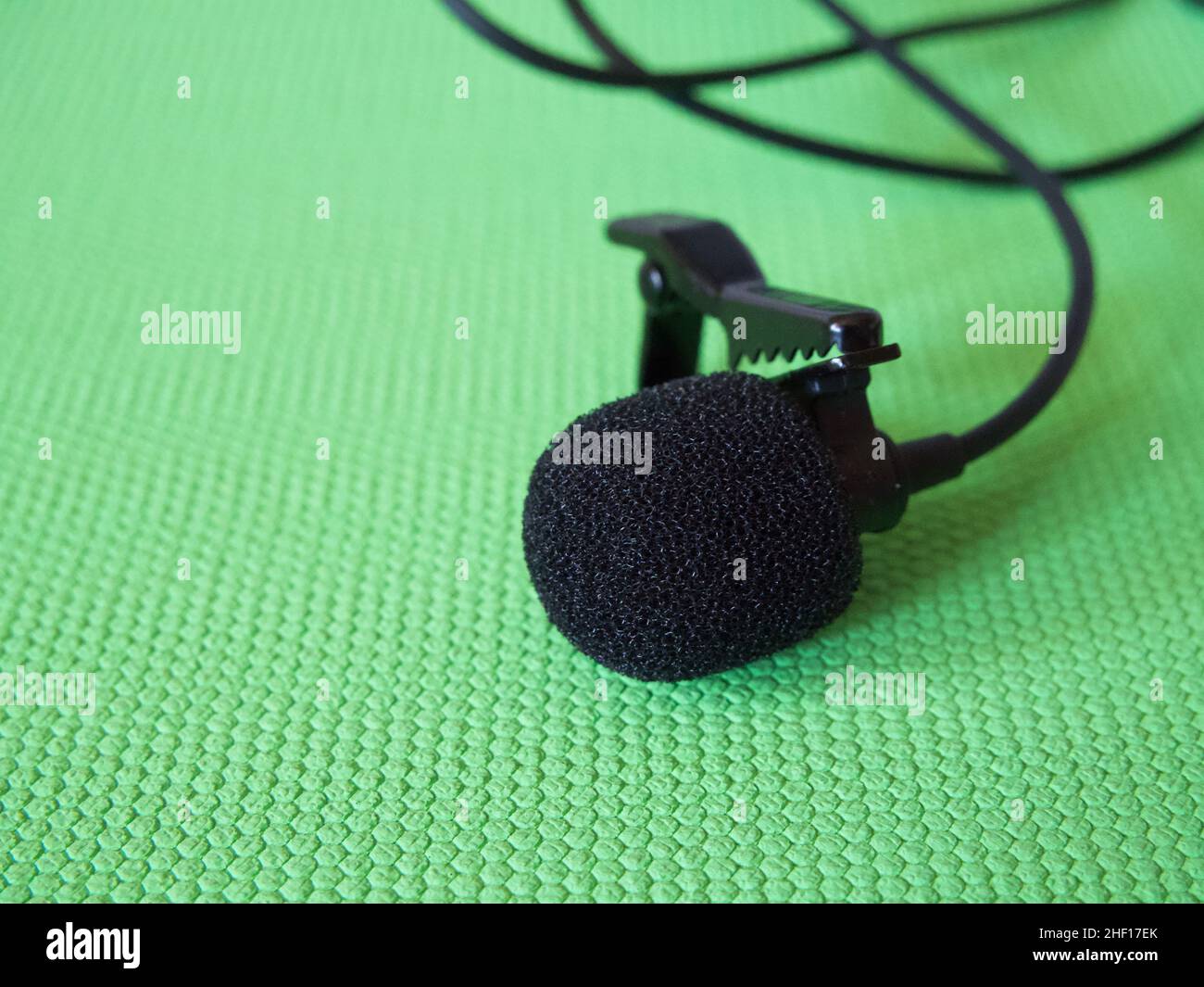 Lavalier microphone on a green background, closeup. A lavalier