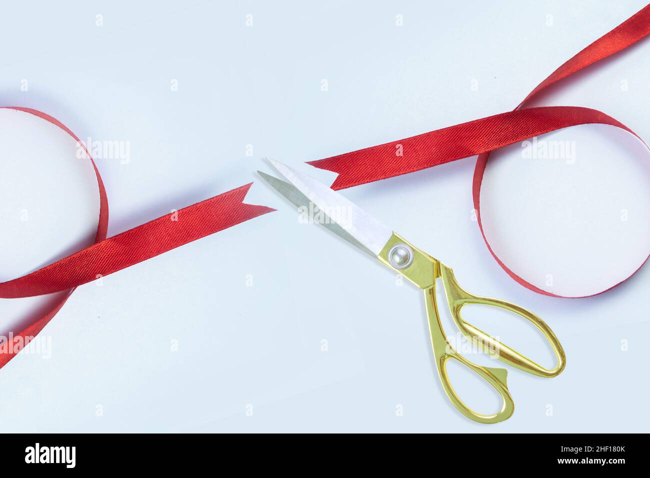 Grand opening, Gold scissors cutting red silk ribbon against White background, Top view, banner, copy space. Stock Photo