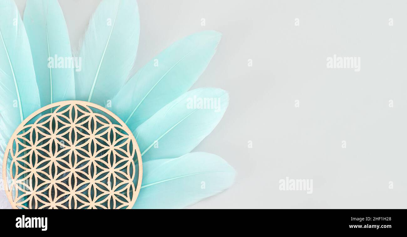 Wooden flower of life symbol with soft feathers. Banner with copy space Stock Photo
