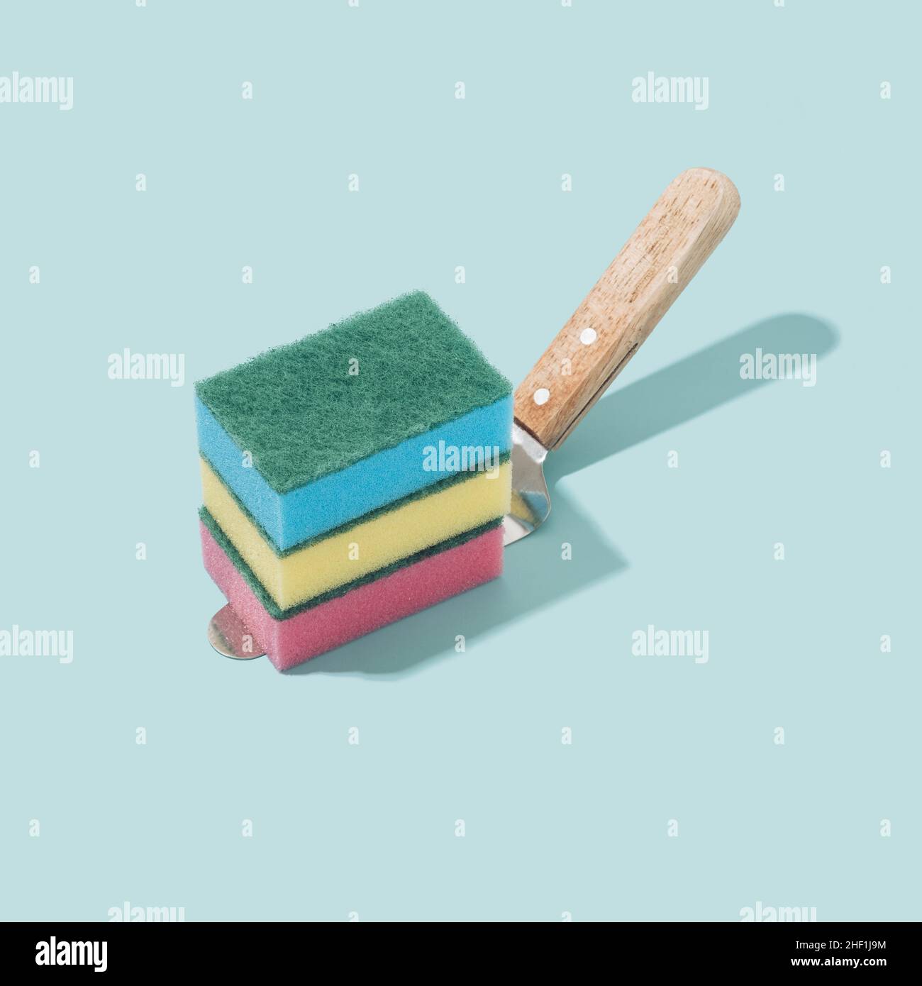 Colorful sponges on a cake spatula and pastel blue background. Immersive reality fantasy concept. Stock Photo