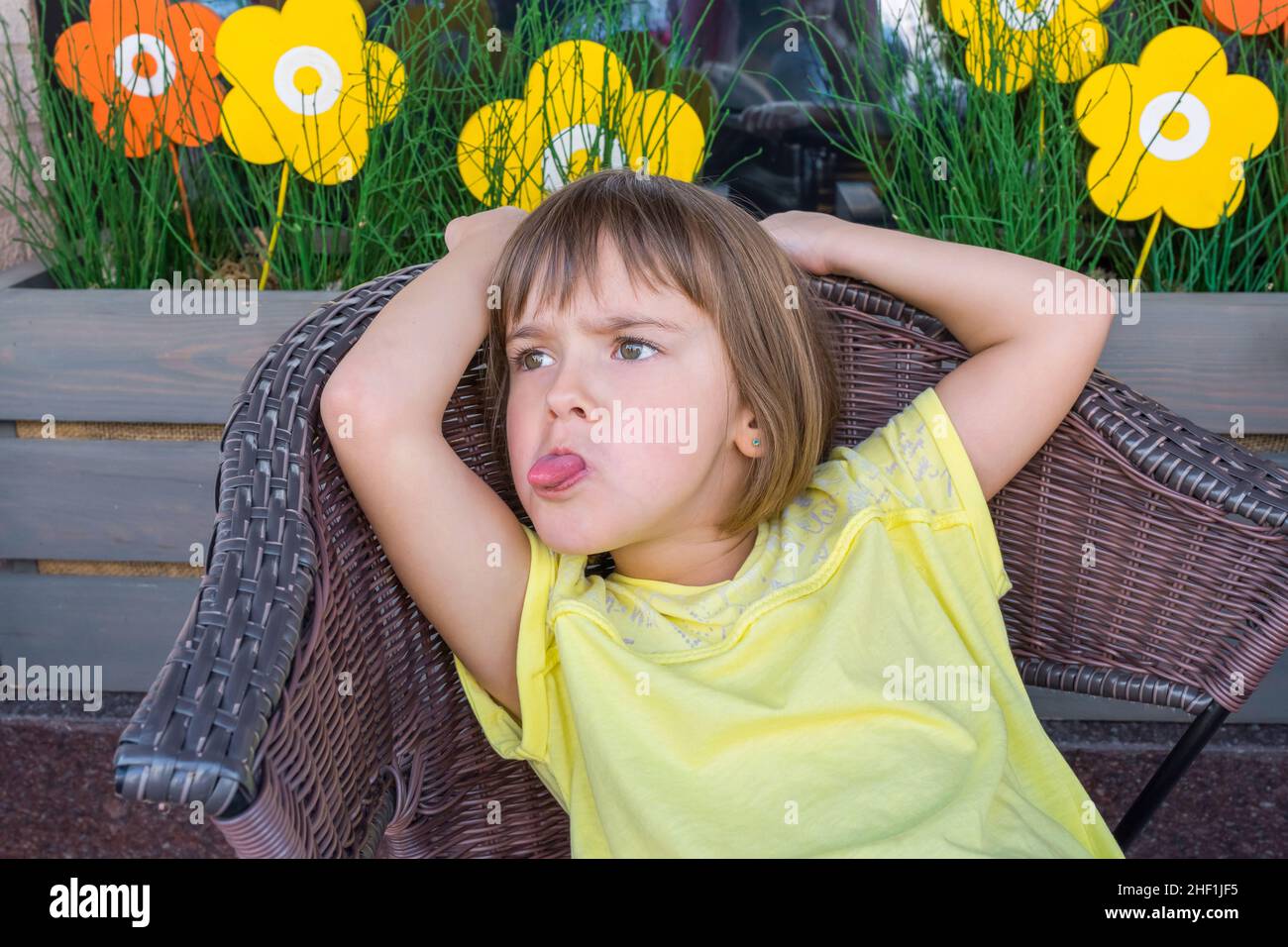 The little girl in cafe puts out the tongue Stock Photo