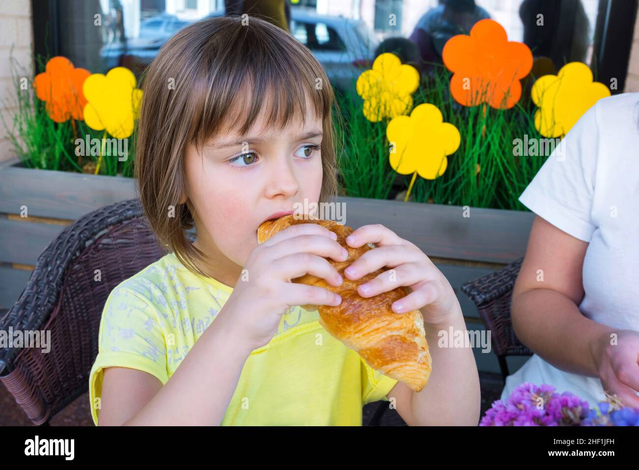 A girl in cafe eats a croissant. Stock Photo