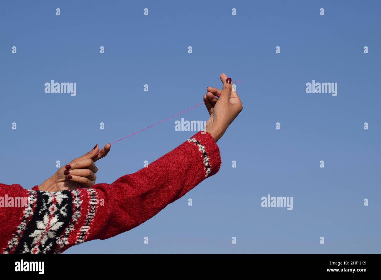 Female holding Kite phirki Manjha or kite spool thread reel in hand and flying kite at house celebrating Indian kite festival of Makar sankranti or Ut Stock Photo