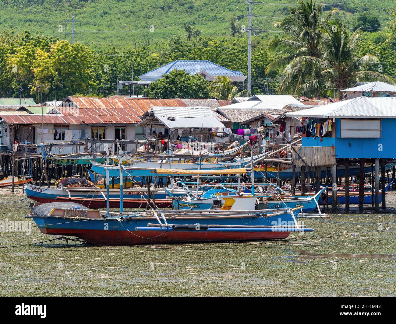 Fishing vessel with outriggers at low tide by the village of