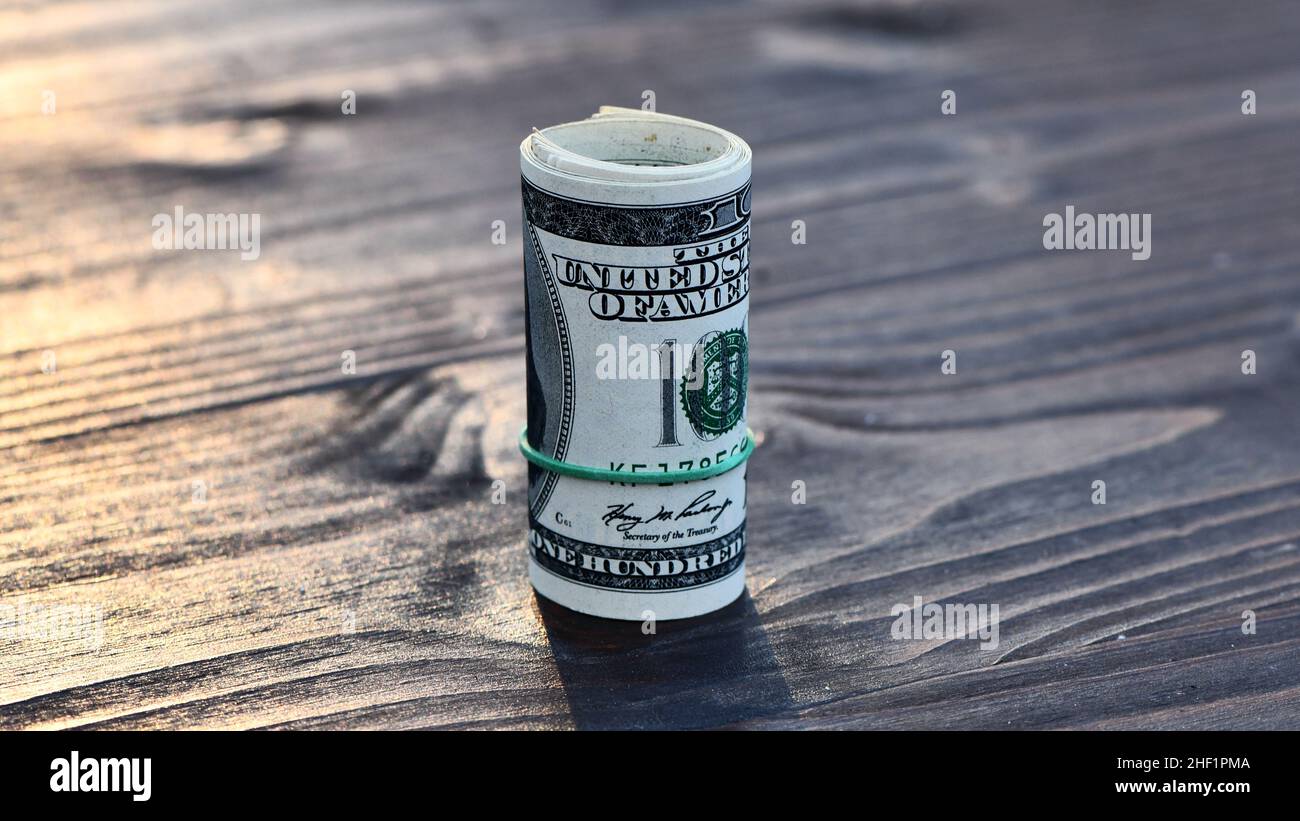 Roll of thousand dollars 1000 dollar in hundred dollar bills isolated on wooden background Stock Photo