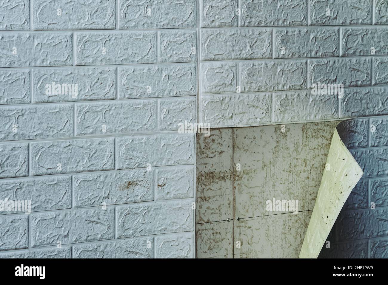 The wallpaper begins to peel off. Old white bricks wallpaper peeled off