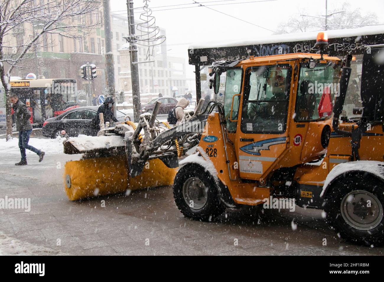 Belgrade, Serbia - January 11, 2022: Removing and clearing a light snowy dusting from city street with sidewalk snow broom vehicle, winter maintenance Stock Photo