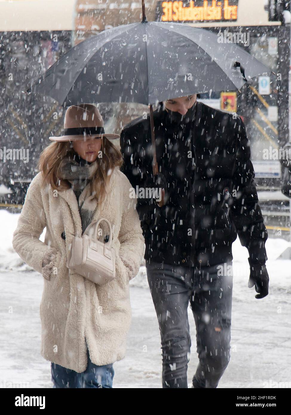 Belgrade, Serbia - January 11, 2022: Two young people walking under umbrella on a snowy winter day in the city Stock Photo