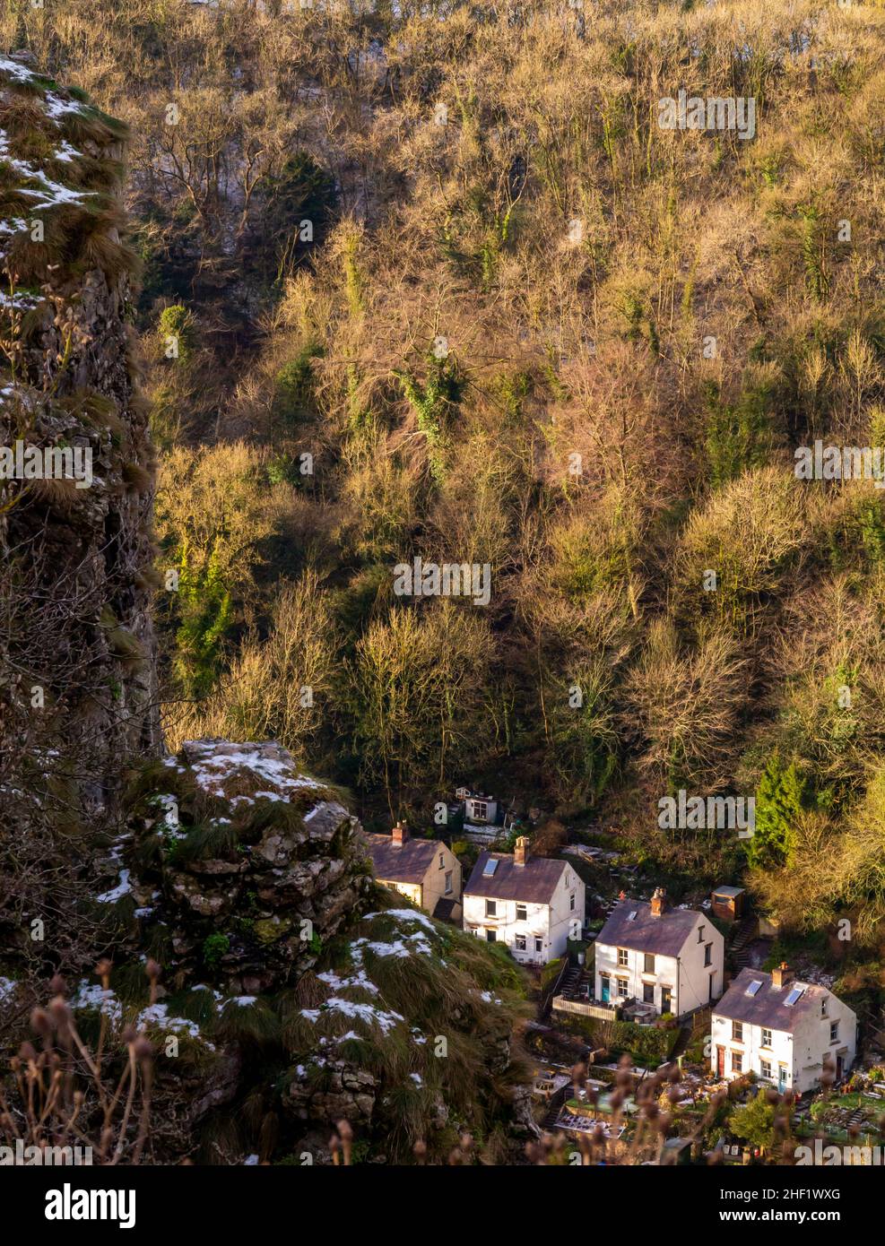 Snow covered landscape with trees at High Tor in Matlock Bath in the Derbyshire Peak District England UK with houses visible in the distance below. Stock Photo