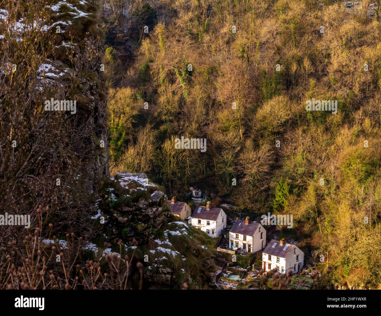 Snow covered landscape with trees at High Tor in Matlock Bath in the Derbyshire Peak District England UK with houses visible in the distance below. Stock Photo