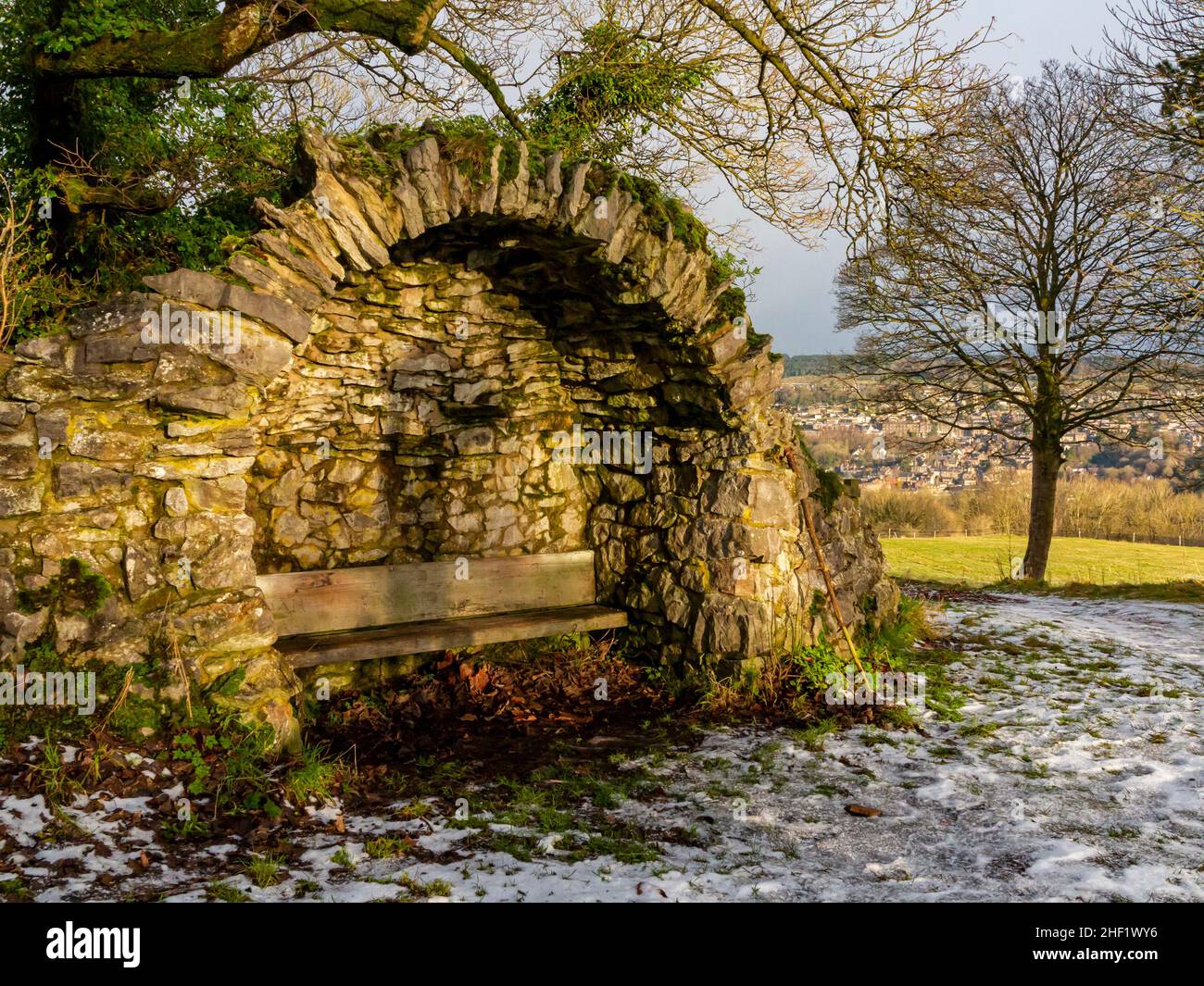 Snow covered landscape with trees at High Tor in Matlock Bath in the Derbyshire Peak District England UK with stone shelter and seat in foreground. Stock Photo