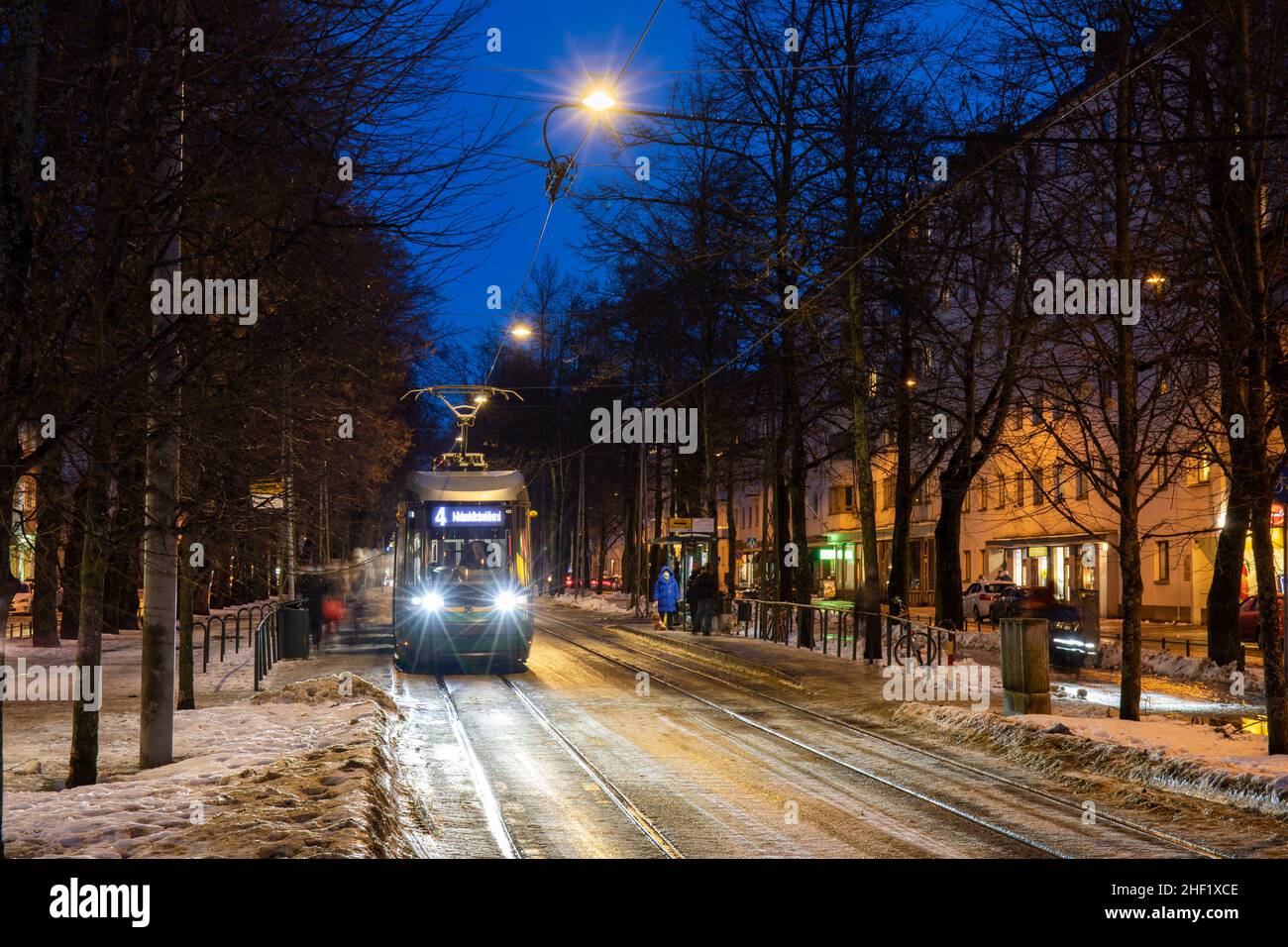 Tram on line 4 at Laajalahden aukio tram stop after dark in Munkkiniemi district of Helsinki, Finland Stock Photo