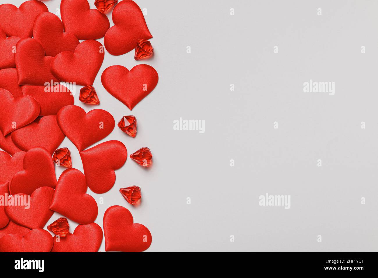 Valentine's Day. Lots of red hearts and crystals on a gray pastel background. Flat lay copy space. Stock Photo