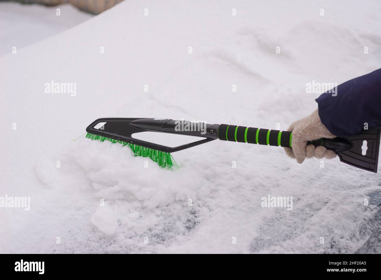 Snow removal, car in snow. Woman cleans the car from snow Stock Photo