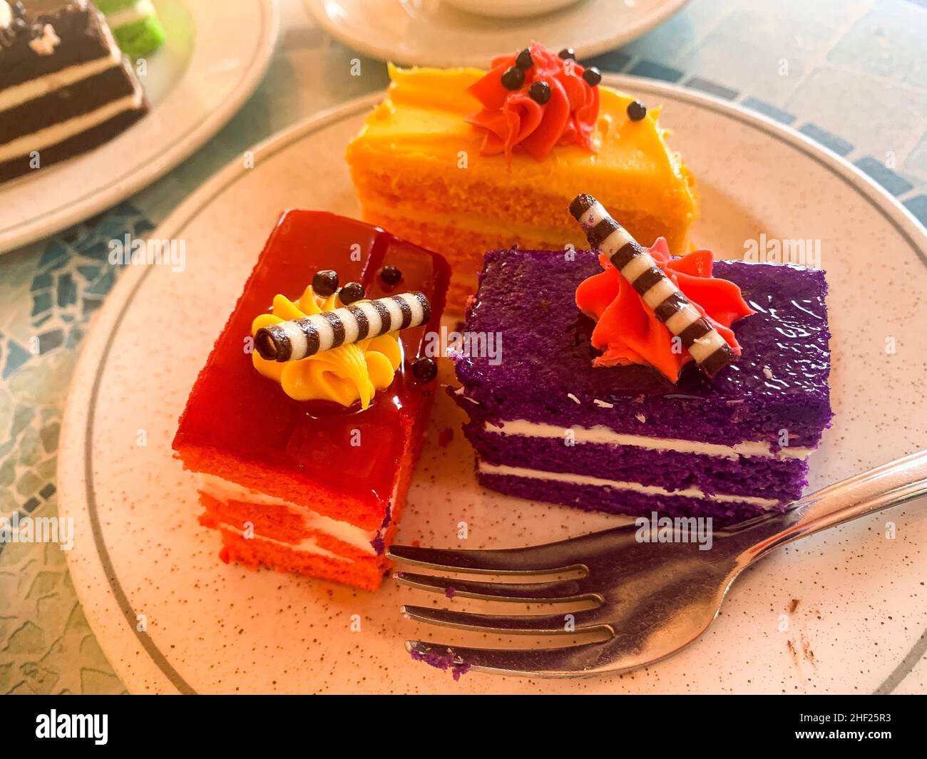 Various colored cakes on plates. Sweet desserts. Photo Stock Photo