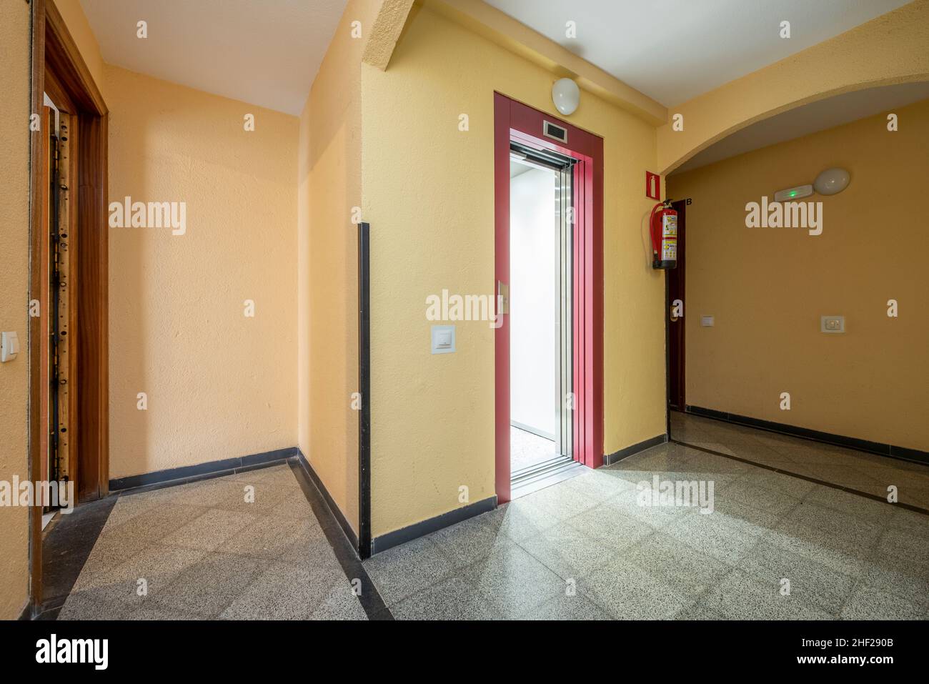 Common areas of a residential building with a red elevator and terrazzo floors Stock Photo