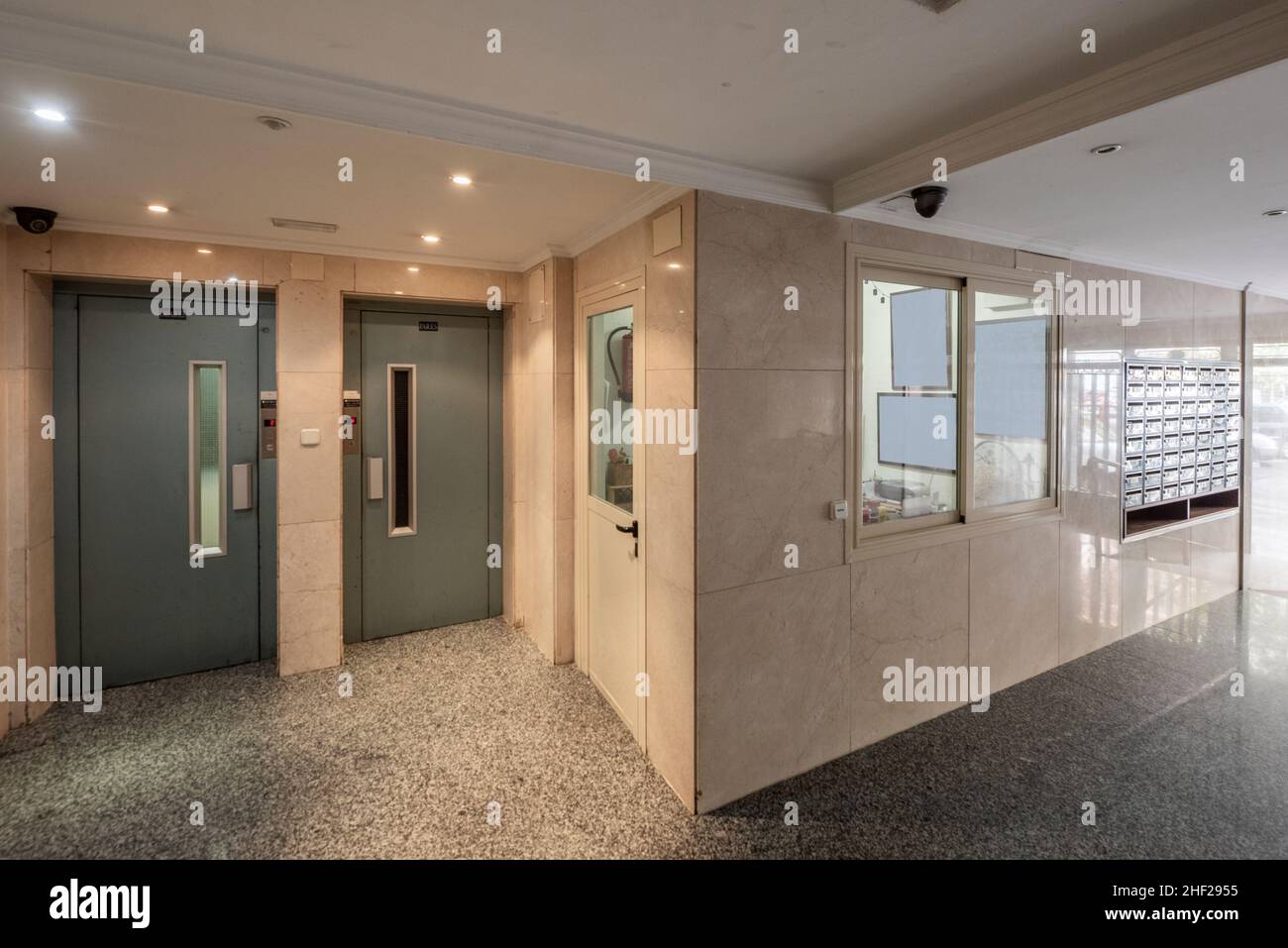 Common areas of a residential building with double elevator with cream marble walls and gray granite floors Stock Photo