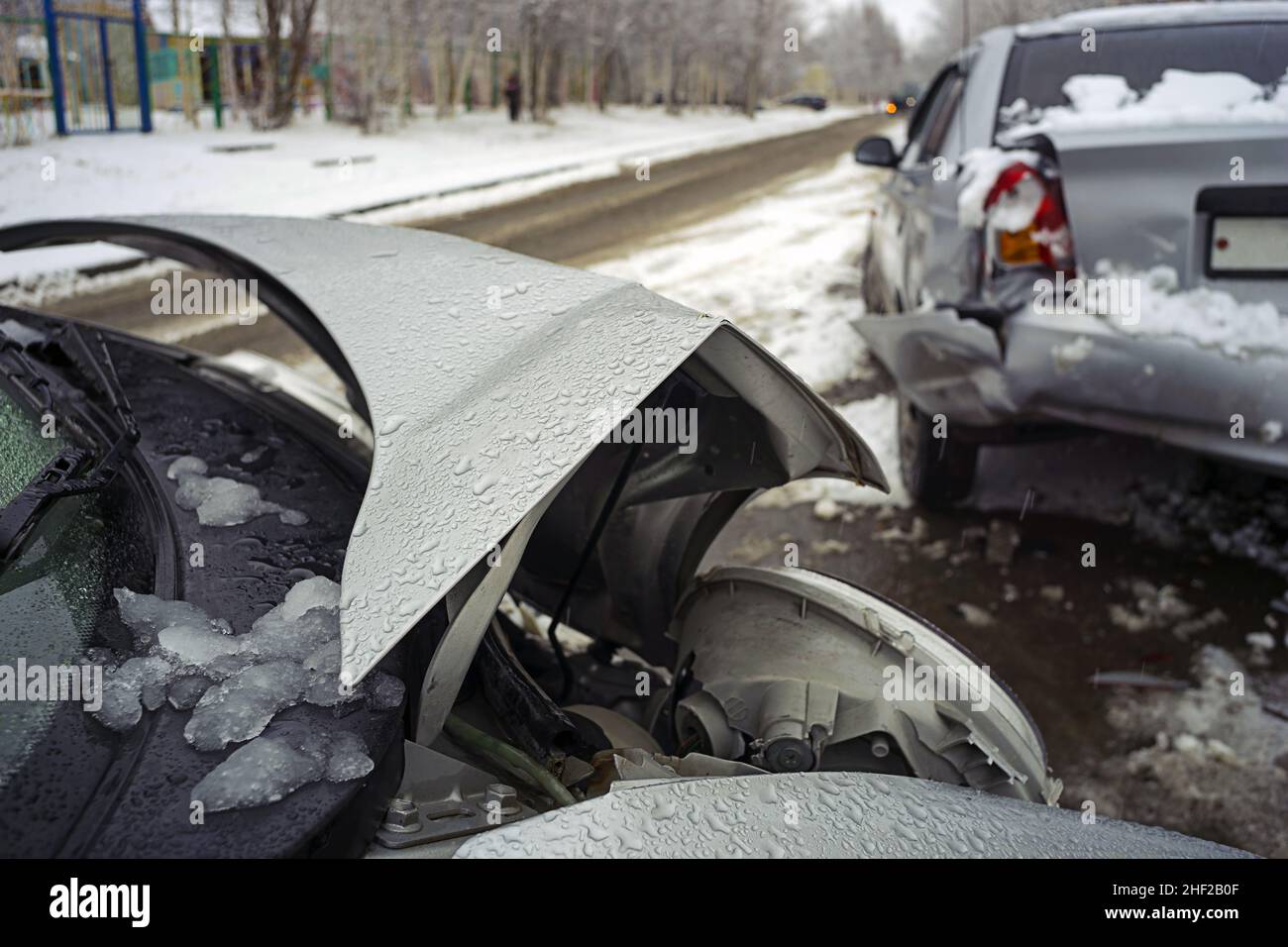 Crumpled car hood accident with two cars in winter on the road. Stock Photo