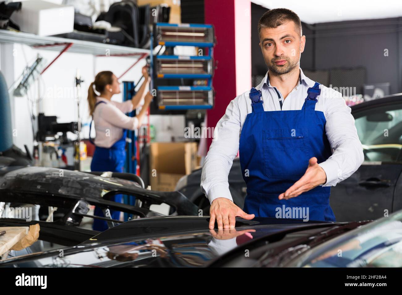 Male worker showing car after repainting Stock Photo