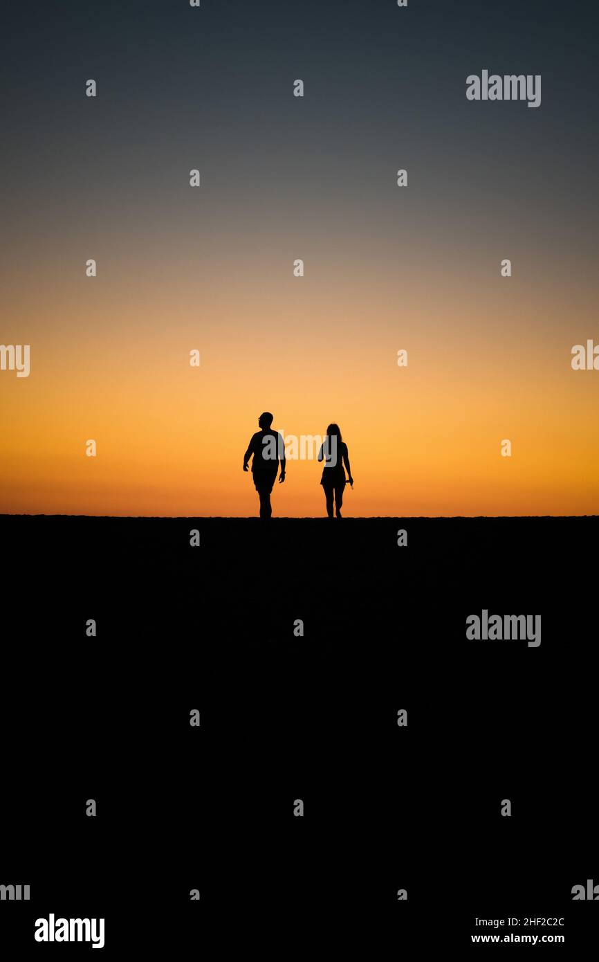 Silhouette of couple at the beach against sunset , post processed using exposure bracketing Stock Photo