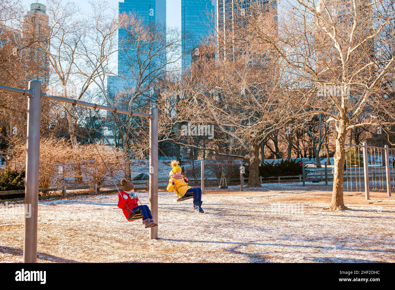 Adorable little girls having fun on the swing in Central Park at New