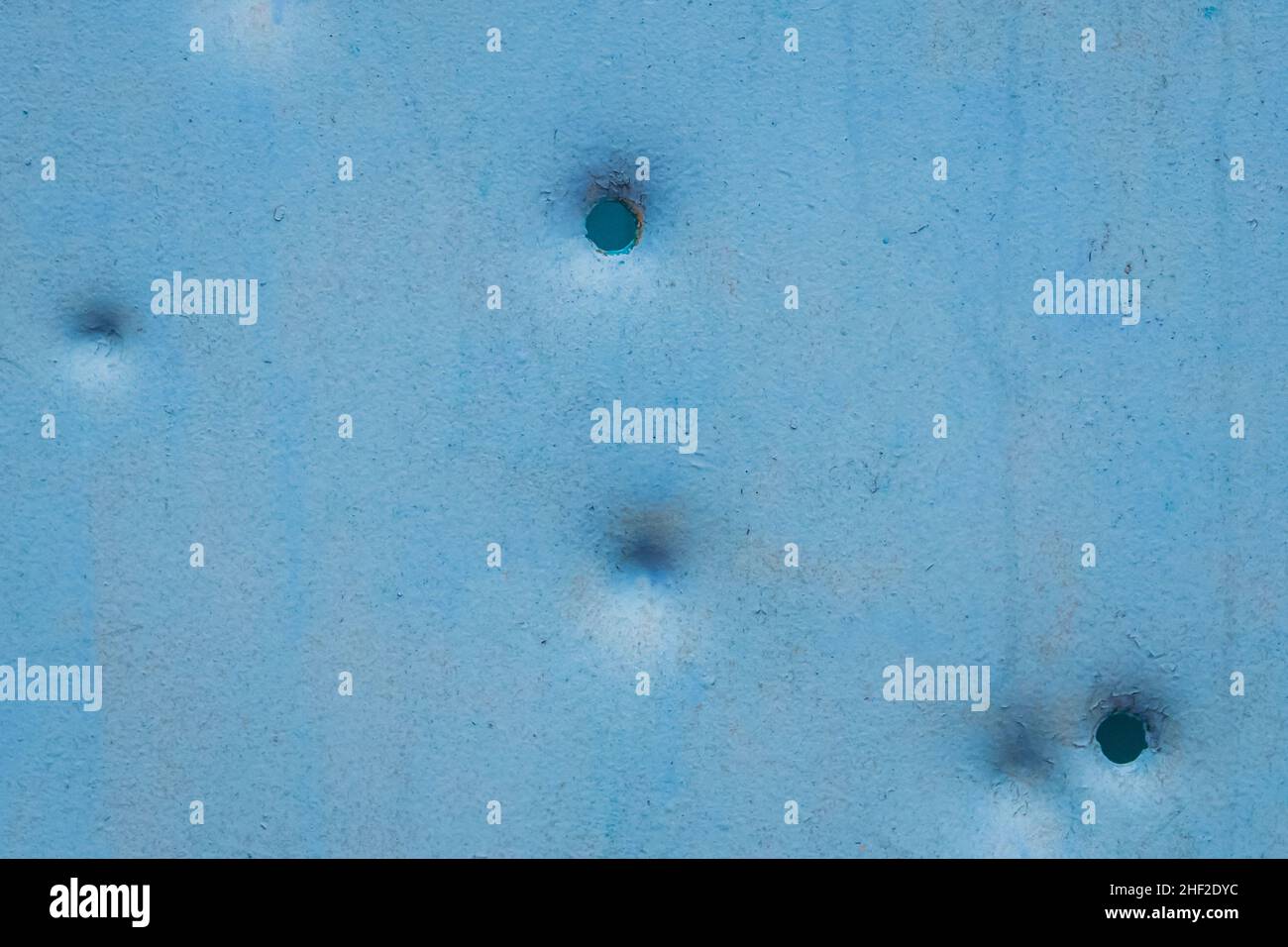 Dents pattern, holes or bullet shot marks on the blue metal surface of the old background iron texture. Stock Photo