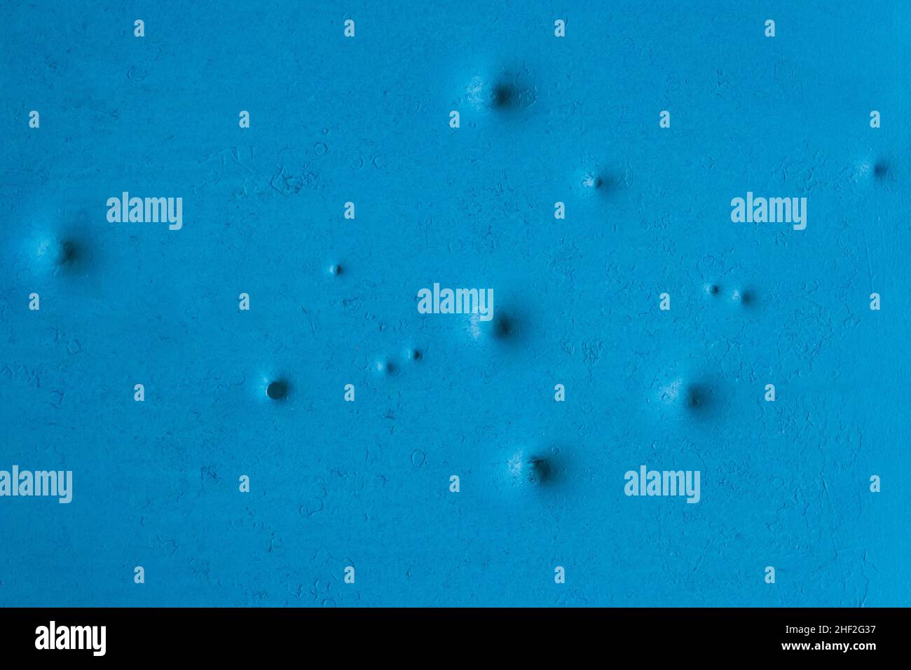 Dents pattern, holes or bullet shot marks on the blue metal surface of the old background iron texture. Stock Photo
