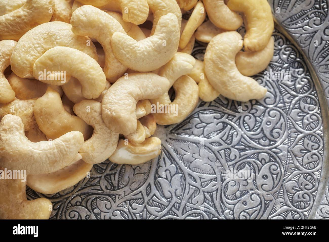 Cashew nuts on a silver plate, selective focus. Stock Photo