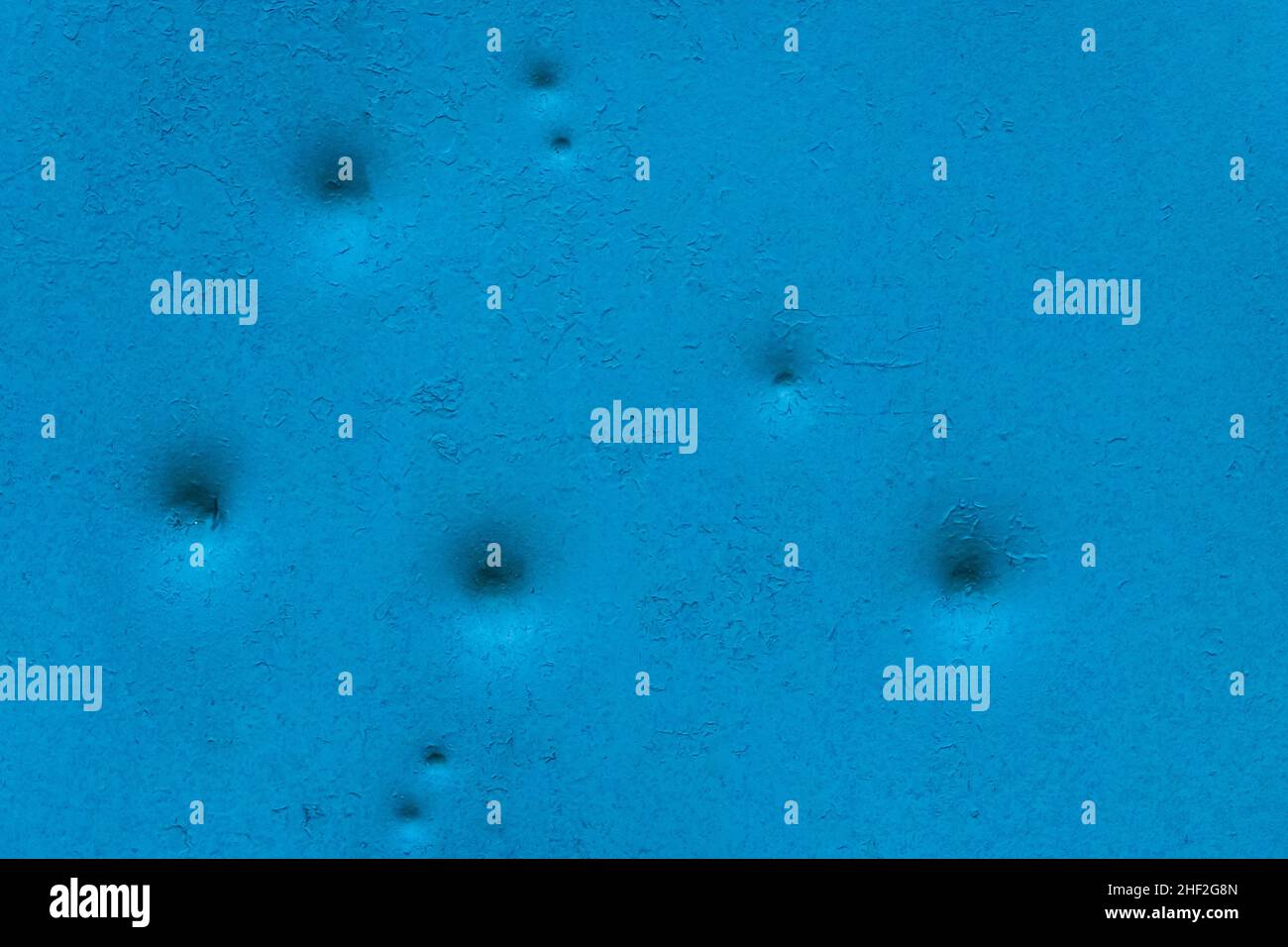 Dents pattern, holes or bullet shot marks on the blue metal surface of the old background iron texture. Stock Photo