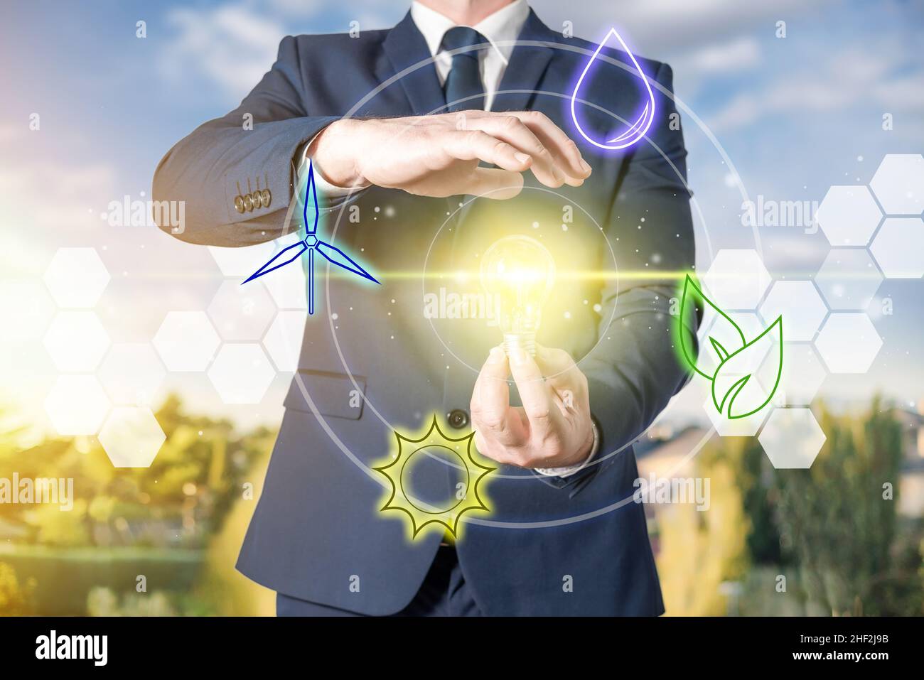 A businessman holds a light bulb lit by using renewable energy. Concept of environmental sustainability, ecology and energy saving Stock Photo