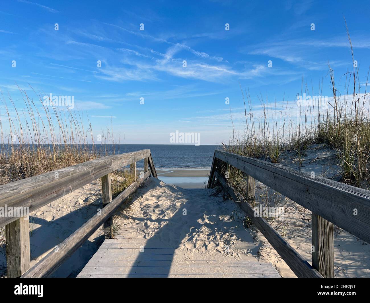 A boardwalk built over huge sand dunes provides access to the quiet southern beaches on Jekyll Island, Georgia, a popular slow travel destination. Stock Photo